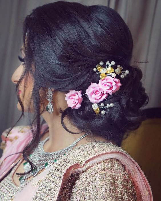 with strands framing the face, the side bun with dainty flowers to complete the look.