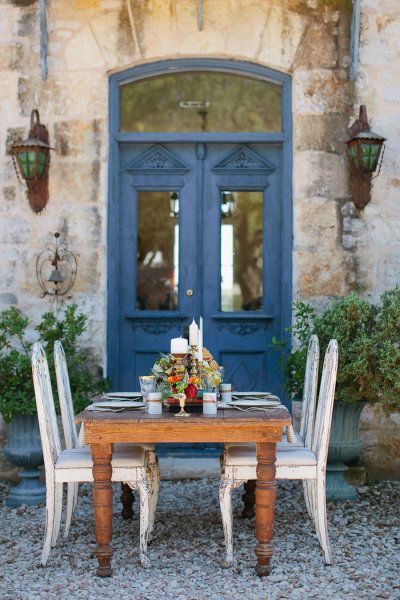 French farmhouse courtyard dining area with blue doors and farm table. #frenchfarmhouse #europeanfarmhouse #courtyard #rustic #dining