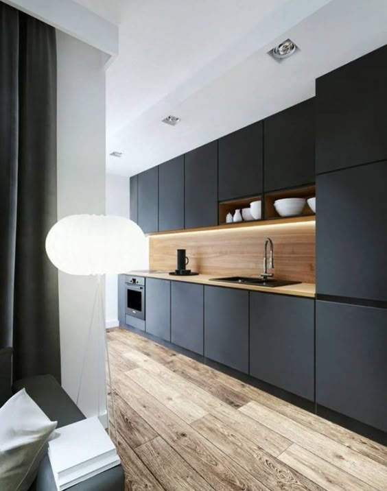 Une cuisine noire mat avec plan de travail en bois clair et un superbe plancher massif.