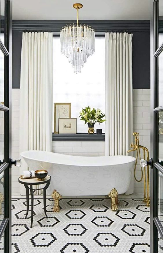 Black and white elegant and luxurious bathroom with crystal chandelier, clawfoot tub, and gold accents. Hexagon black and white tile flooring plays a starring role! #blackandwhite #elegantdecor #bathroomdecor