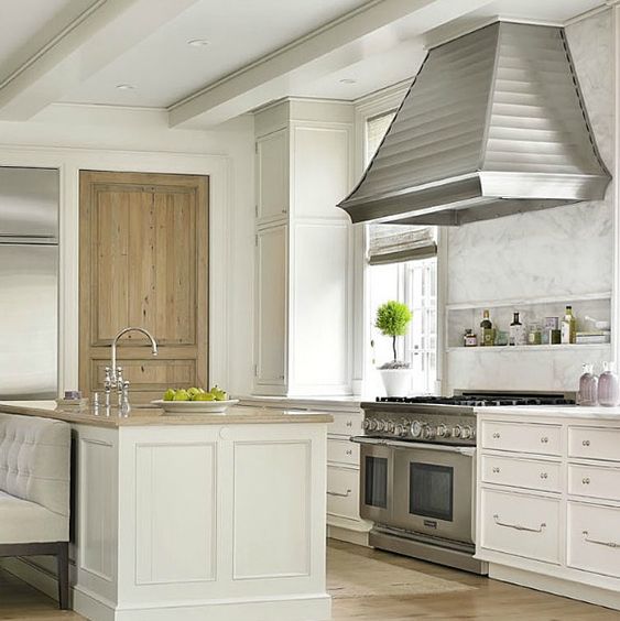 White kitchen beauy! Interior design ideas photo gallery featuring understated kitchen with design by Phoebe Howard for a traditional and classic limestone manor home in Charlotte. Wormy chestnut wood pantry door and glossy white cabinetry mix beautifully. #kitchen #interiordesign #traditional #whitekitchen #classic