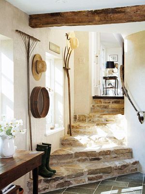 Love the flagstone stairs, beamed ceiling, and light. - I want to live here! This informal back entrance, which leads inside from a garden, has the feel of an old European cottage. Unusual decorative touches, such as the wall-hung wooden rake, pitchfork and sifter, echo the rustic textures in the flagstone steps and wood beam.