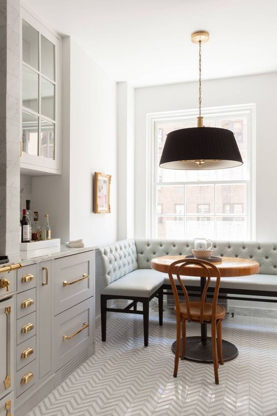 Classic kitchen design with grey cabinets, #brasshardware, tufted #banquette, Bentwood chair, and round bistro table - on Hello Lovely Studio