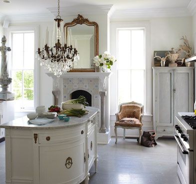Romantic and feminine white kitchen with farmhouse style, fireplace, crystal chandelier, delft tiles, and unique repurposed island. Design by Annie Brahler Smith. #whitekitchen #countrykitchen #european #frenchcountry