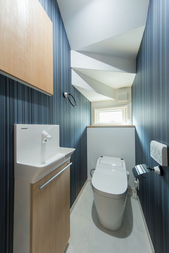 階段の下の空間を活かして作られたトイレは、濃紺のクロスを使って高級ホテルの趣に。 #トイレ\u3000#ブルーのブルーの壁紙\u3000#タンクレストイレ\u3000高級感のある空間\u3000#ラビングホーム\u3000#不動産\u3000#建築\u3000#施工事例
