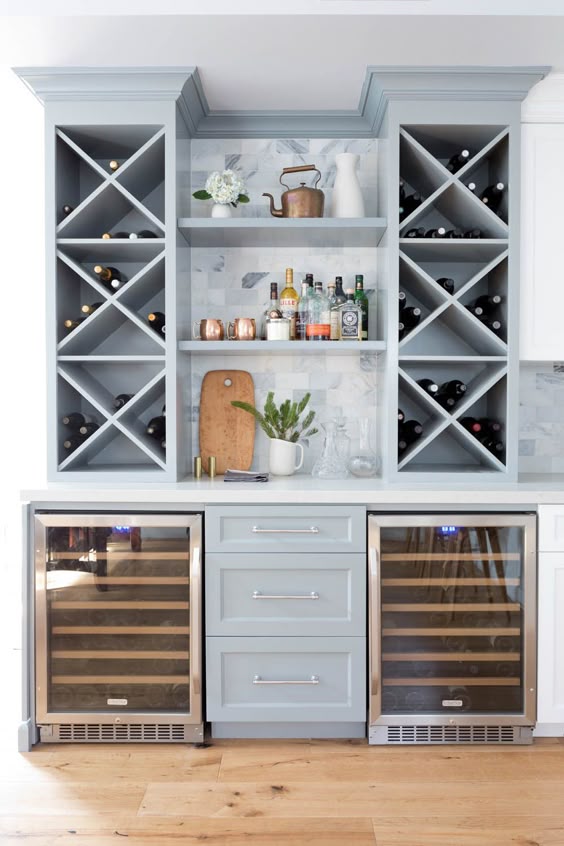 Personalized home coffee bar ideas - blue kitchen cabinets, marble backsplash, and two wine refrigerators.
