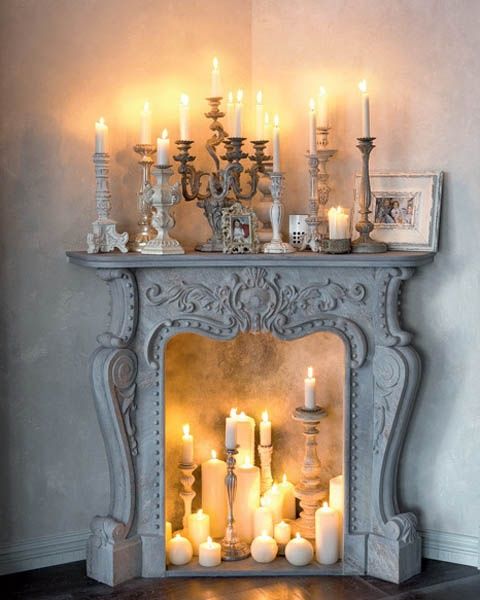 Elegant ornamental French stone fireplace filled with candles and candlesticks
