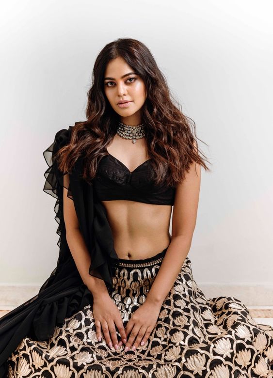 Bindu Madhavi posing on the floor wearing a beautiful black lehenga designed by Chaitanya Rao.
