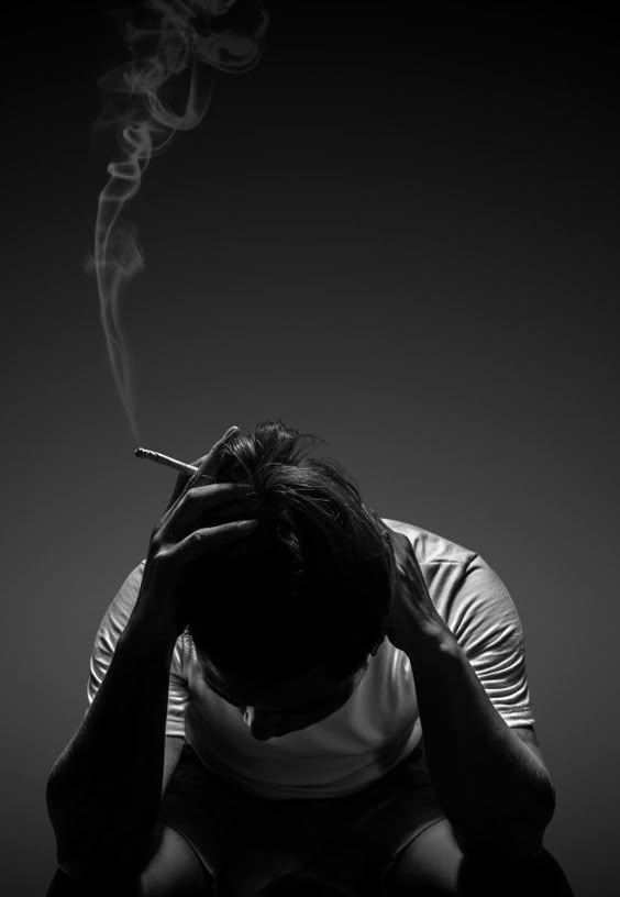 Premium Photo | Depressed man smoking cigarette sitting on chair on black