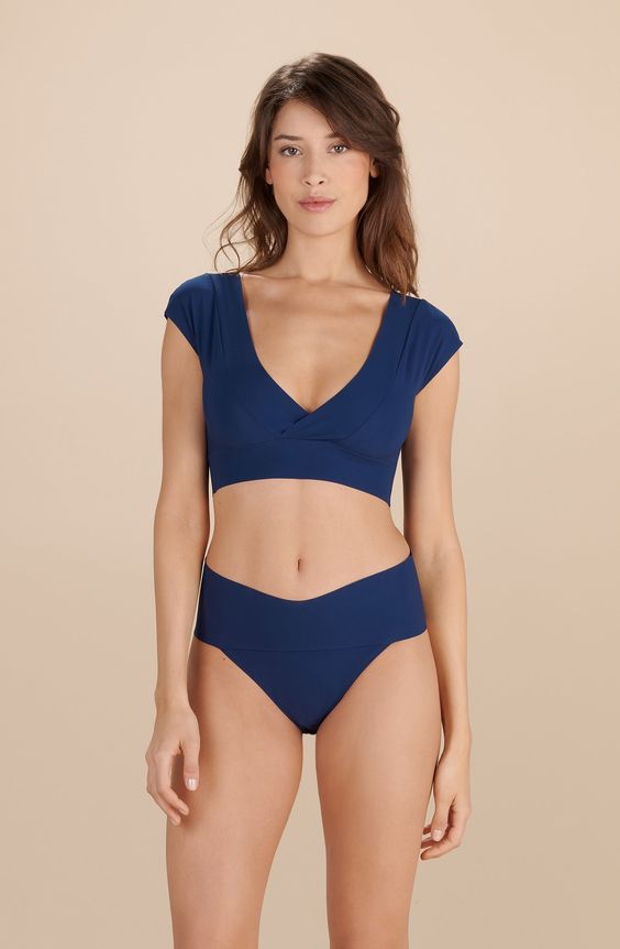 Crop-top décolleté en V devant et dos, manches courtes, large bande sous poitrine, finitions free cut.71 % polyamide, 29 % élasthanneNé dans les années 60, le crop-top traverse les époques sans prendre une ride. Le « haut raccourci » est devenu la pièce incontournable de notre dressing. Avec ANJALI nuit, on s’offre un top ultra confort au look un brin sporty et on ose dévoiler sans complexe nos formes et notre joli bronzage. Avec ses décolletés devant et dans le dos et sa bande sous-poitrine en