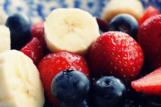 12 alimentos que te embellecen bodegón de frutos rojos, fresas y arándanos, con rodajas de plátano