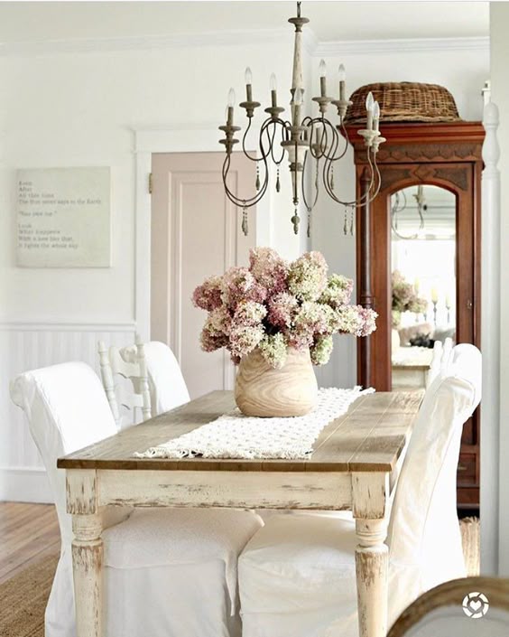 Shabby chic dining room with blush flowers, French chandelier, and slipcovered chairs. #shabbychic #diningroom #hydrangea