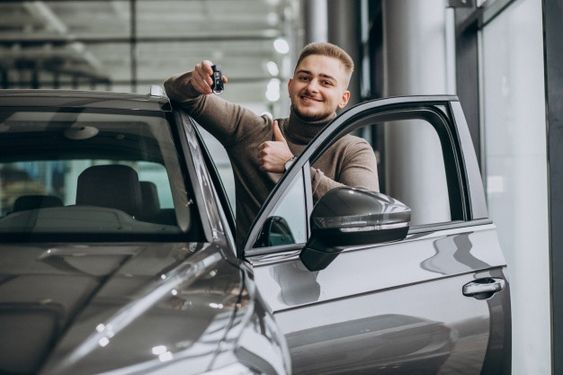 Free Photo | Young handsome man choosing a car in a car showroom