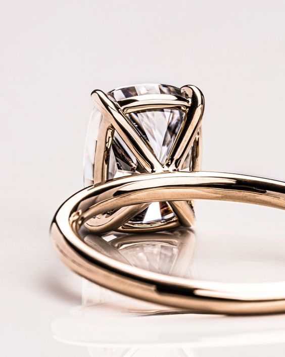 9x7mm (2.4 carat equivalent) crushed ice cushion 4-prong Randi Moissanite engagement ring featuring a classic X prongs, a plain rail and a plain band in 14k yellow gold, size 5.5.✨ Zen Moissanite jewelry pieces are custom made, ethical and durable Diamond alternatives.