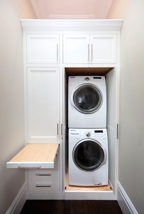 a white washer and dryer in a small room with built - in cabinets