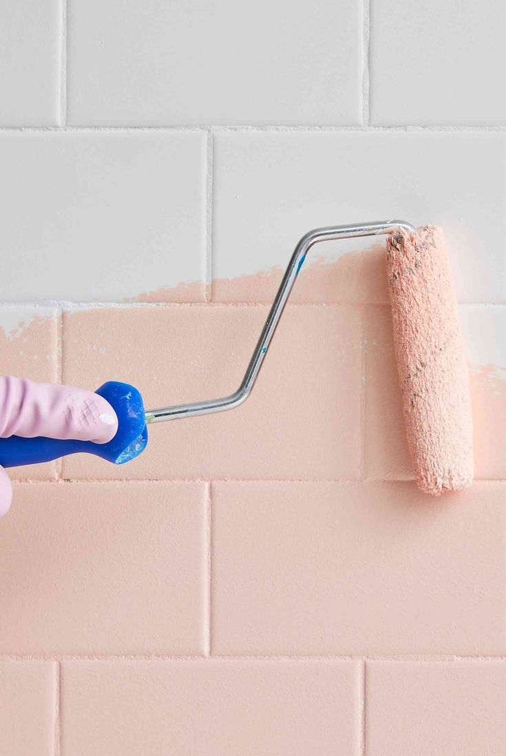a person using a roller to paint a pink brick wall with pastel colors on it
