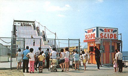 a group of people standing on top of a sandy beach next to a tall fence