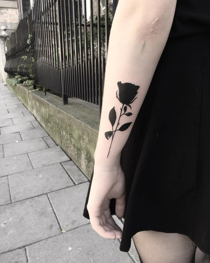 a woman with a black rose tattoo on her arm