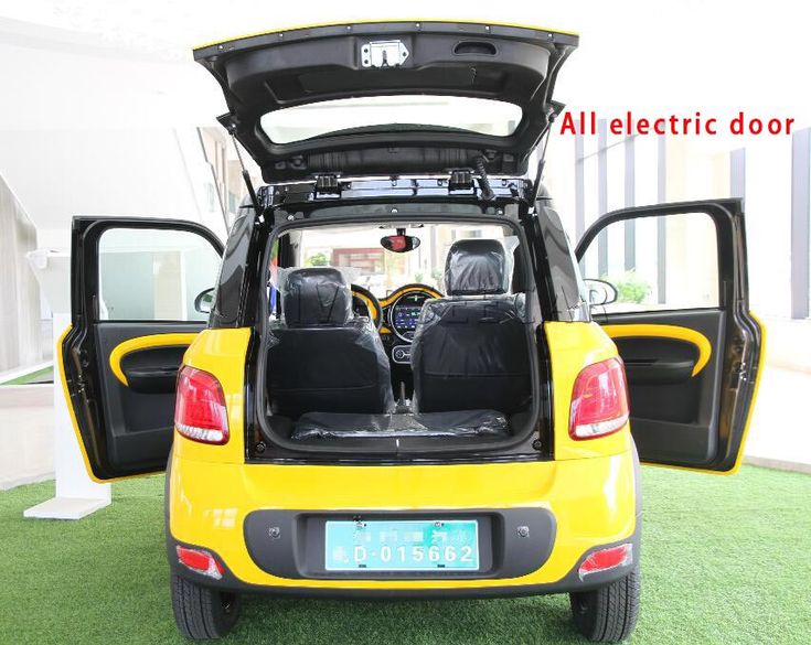 the back end of a small yellow car with its doors open and seats folded down