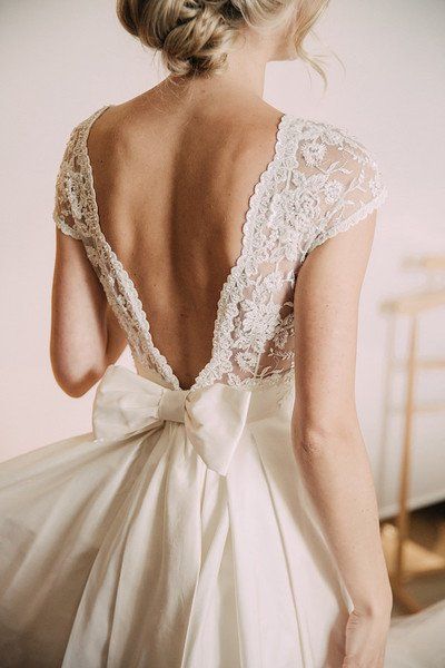 the back of a woman's wedding dress with a large bow on her head