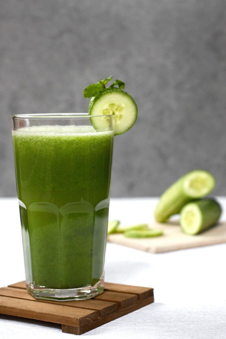This may contain: a green smoothie with cucumbers on the side