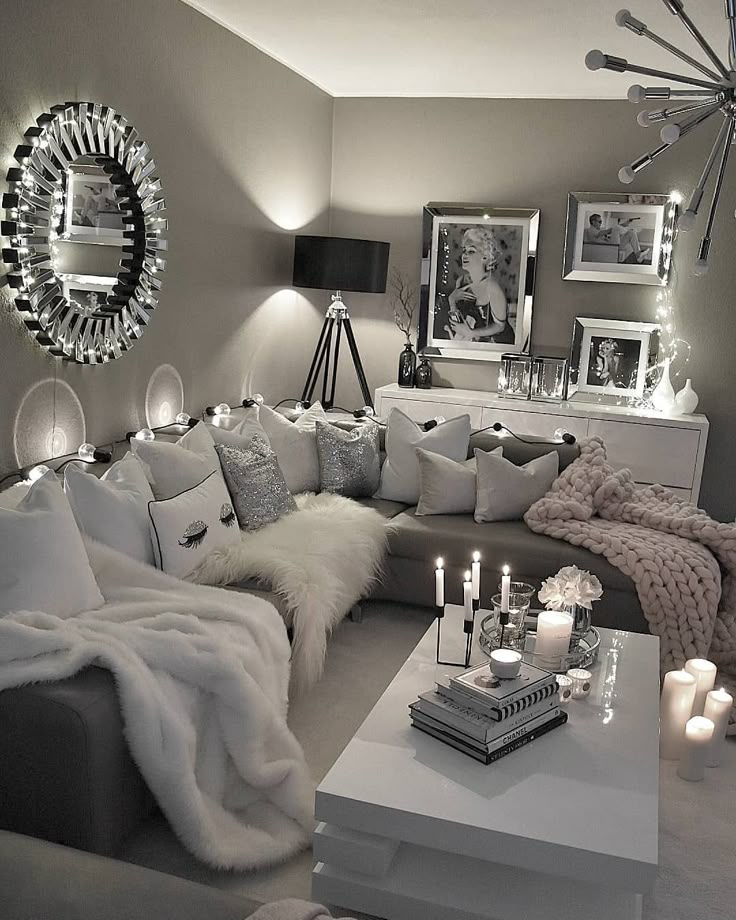 a living room filled with lots of white furniture and candles on top of the coffee table