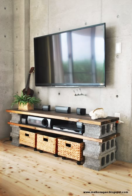 a flat screen tv mounted to the side of a wall in a living room with baskets underneath it