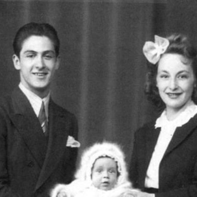 an old black and white photo of two people holding a baby in front of them