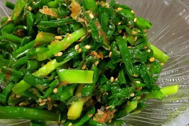 a glass bowl filled with green vegetables on top of a table