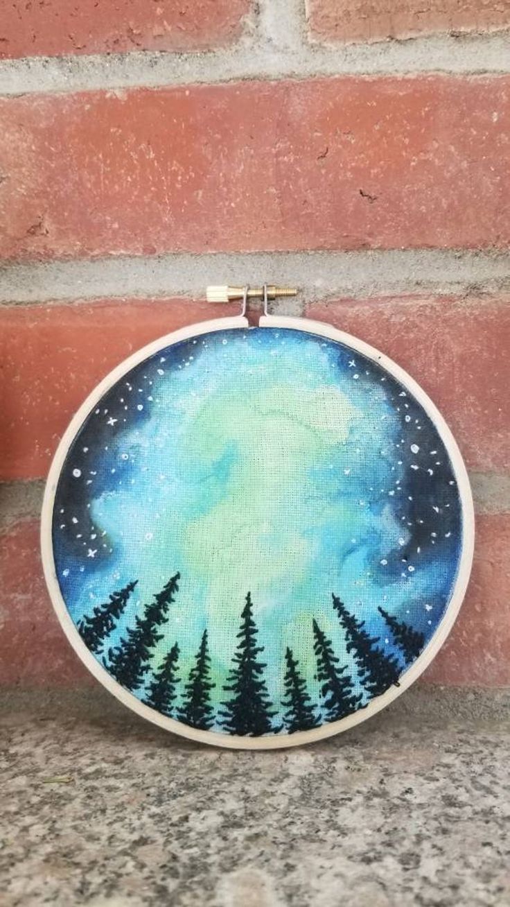 a hand painted hoop hanging on the side of a brick wall with trees in