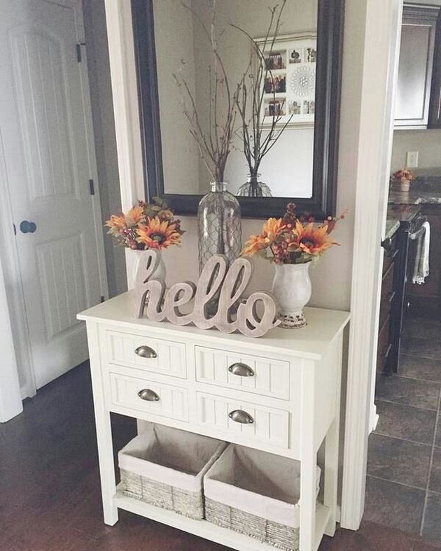 there is a white dresser with two vases on it and flowers in front of the mirror