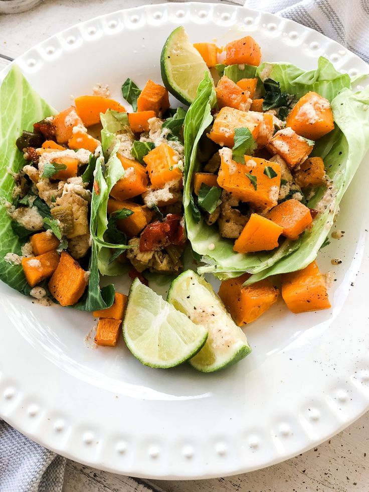 two lettuce wraps filled with chicken, carrots and avocado on a white plate