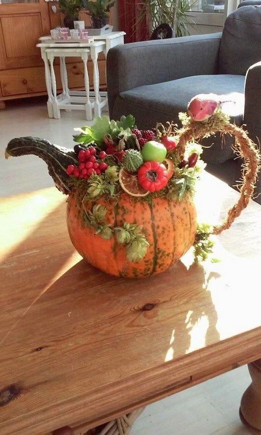 a pumpkin decorated with berries, leaves and other decorations on a table in a living room