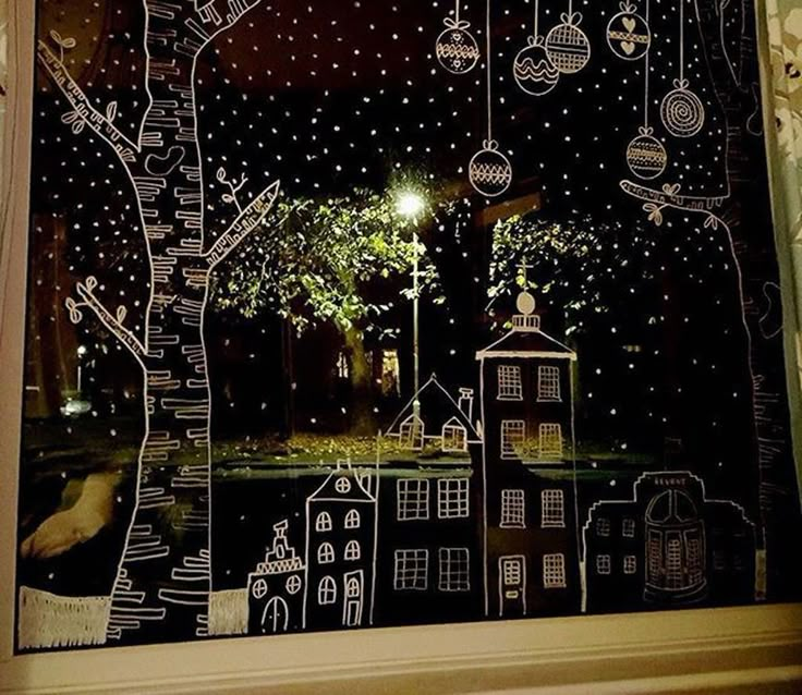 the window is decorated with white and black paper cut outs, trees, houses, and street lights