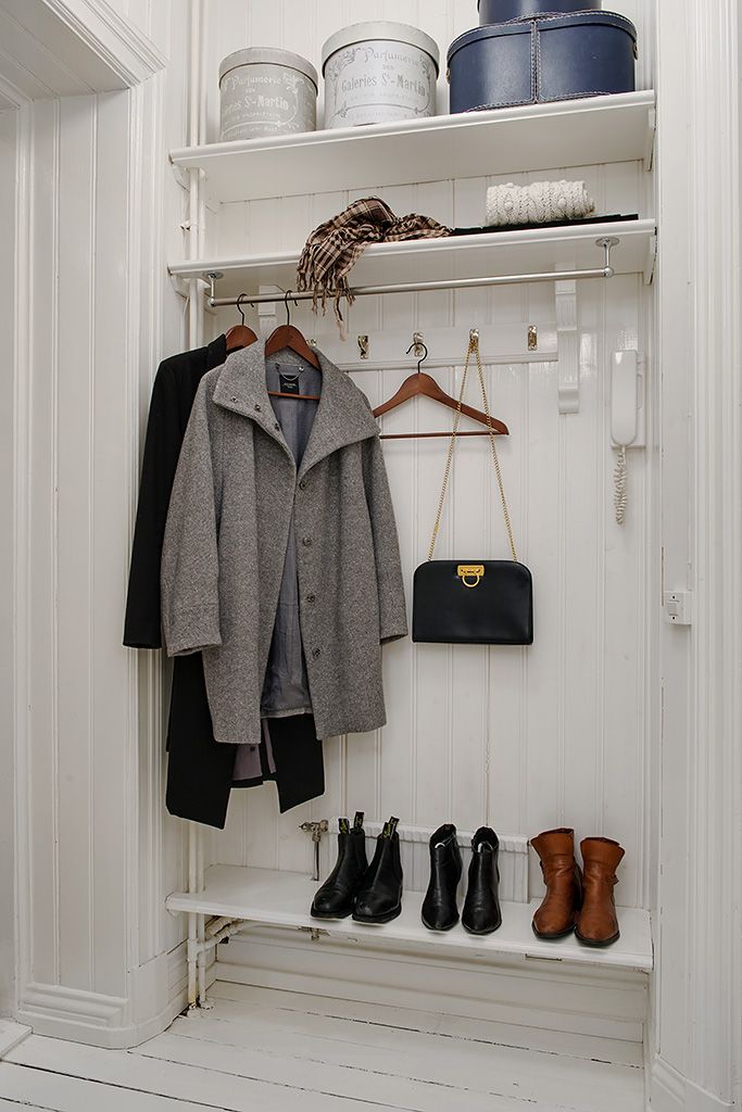 a coat rack with shoes and handbags hanging from it's hooks in a white closet