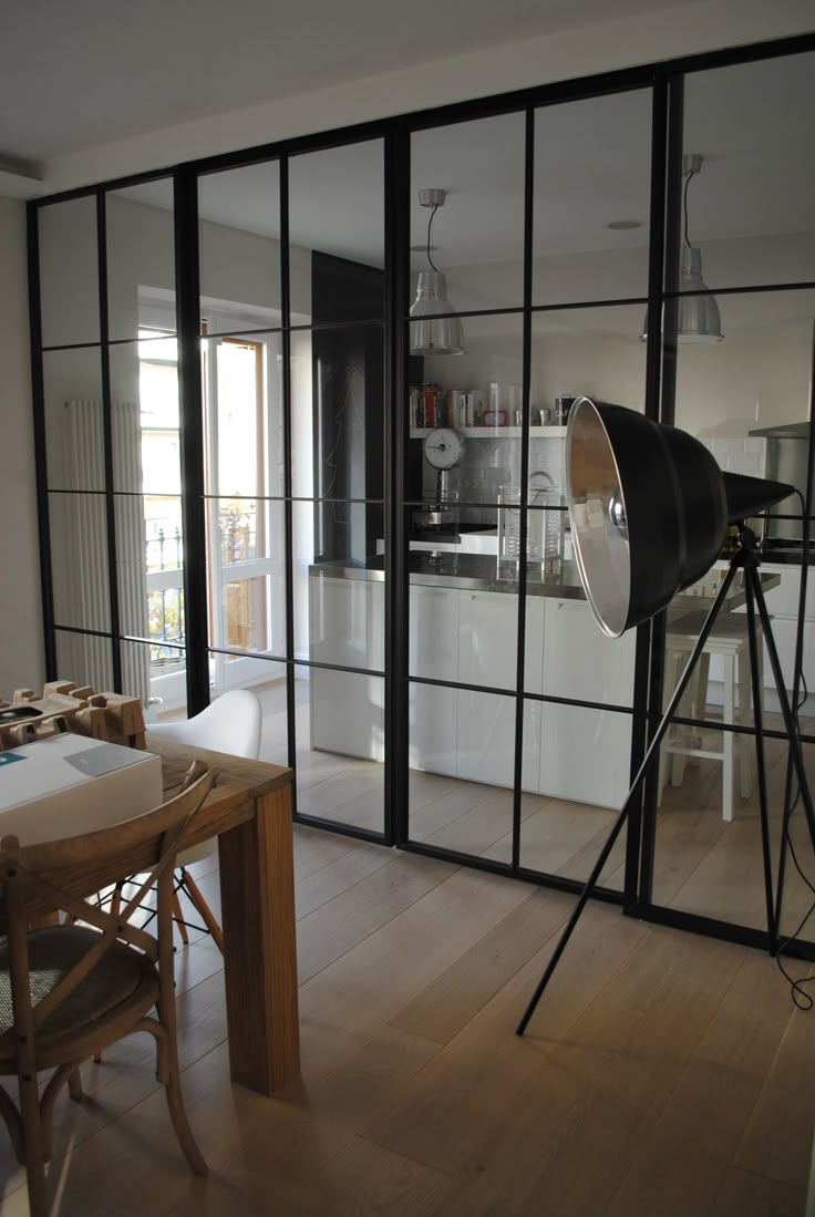 a dining room table and chairs in front of large glass doors that lead into the kitchen