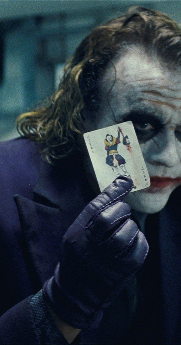 The Joker Holding Up A Card In His Hand