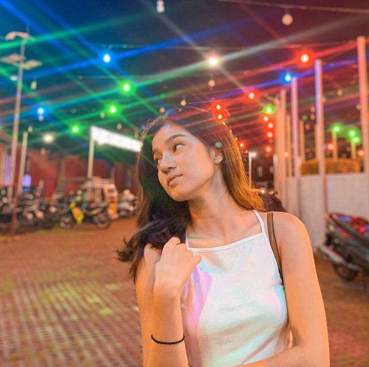 a woman standing in front of a building with colorful lights on it's ceiling