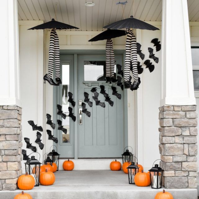 a front porch decorated for halloween with pumpkins and black bats hanging from the ceiling