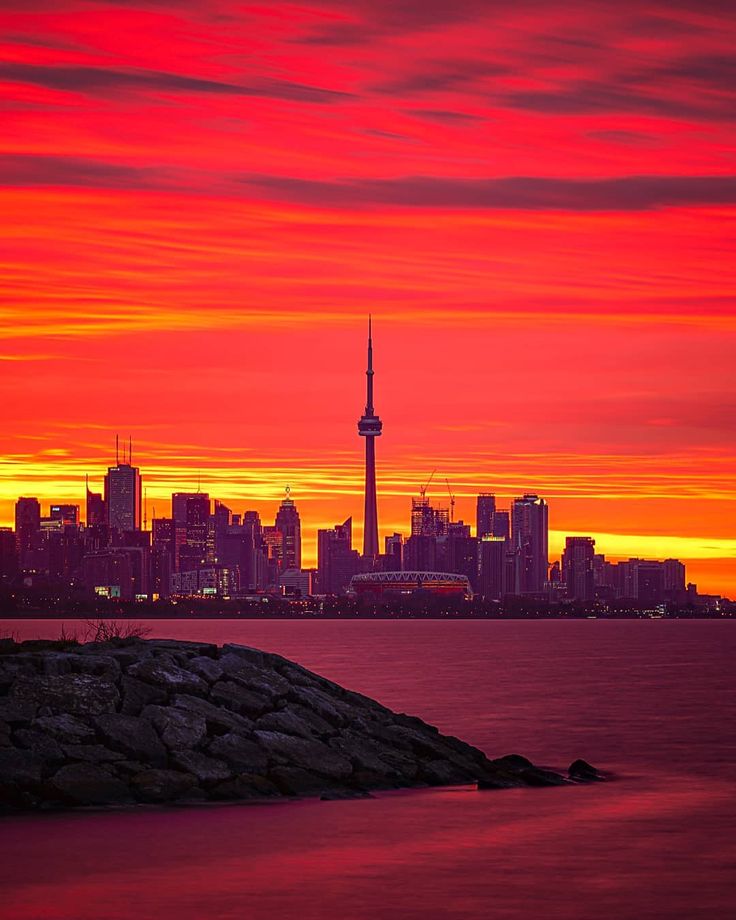 the sky is red and orange as the sun sets over the city skyline in ...