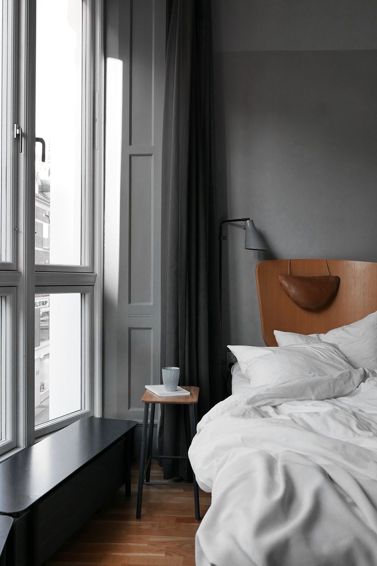 a bed sitting next to a window with white sheets and pillows on top of it