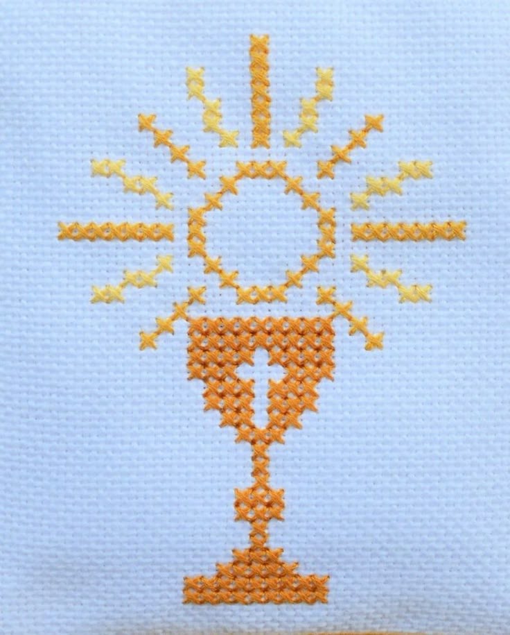 A Cross Stitched On Top Of A White Pillow With An Orange And Yellow Design A Cross Stitched On Top Of A White Pillow With An Orange And Yellow Design