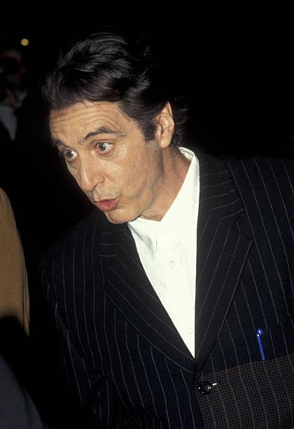 a man in a pinstripe suit looks at the camera while standing next to