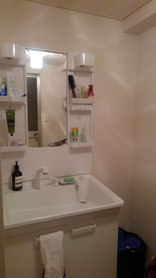 a bathroom sink sitting under a mirror next to a wall mounted shelf with soap and toothbrushes