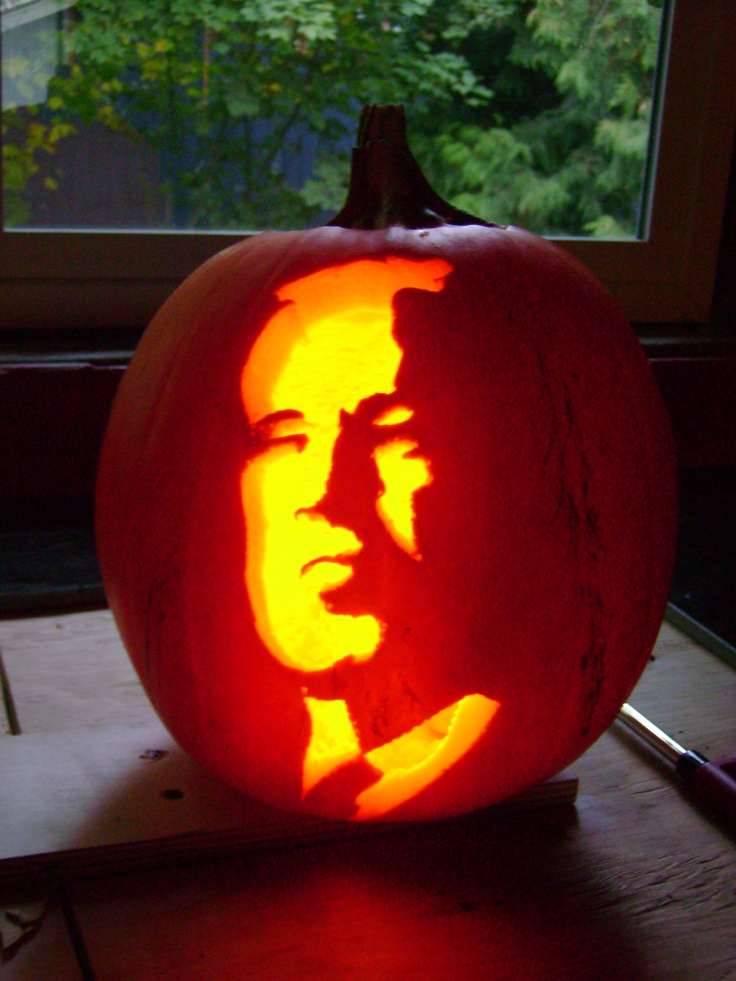 a-pumpkin-carved-to-look-like-abraham-lincoln-is-shown-in-front-of-a-window-with-trees-outside