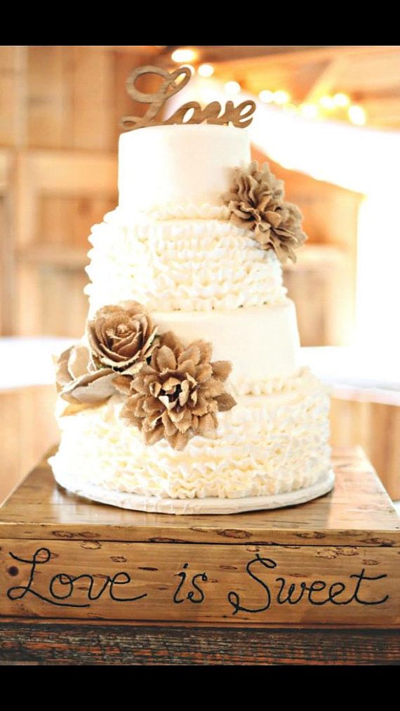 a wedding cake with pine cones on top and love is sweet written on the side