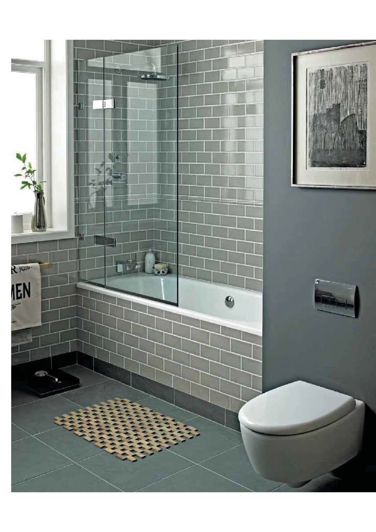 a white toilet sitting next to a bath tub in a bathroom with gray walls and tile flooring