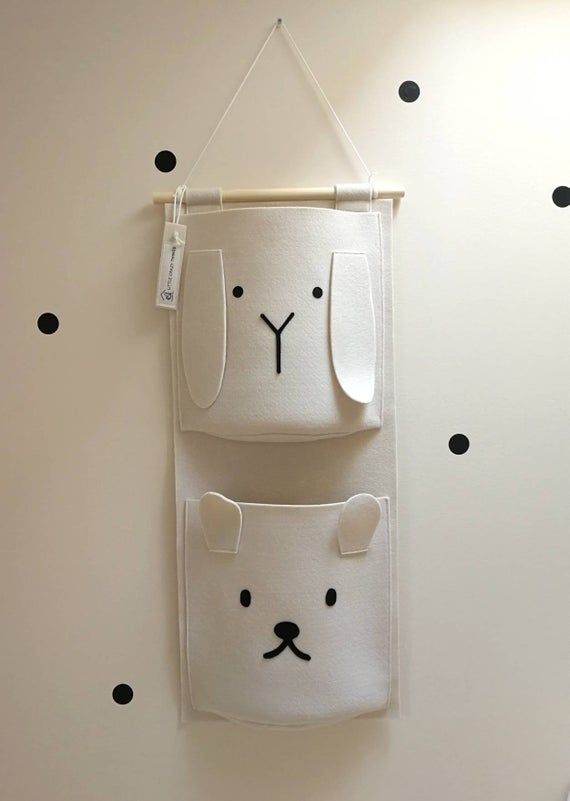 a white wall hanging with black polka dots on it and two bears in the middle