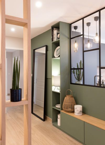 the interior of a house with green walls and wooden floors, plants in pots on shelves