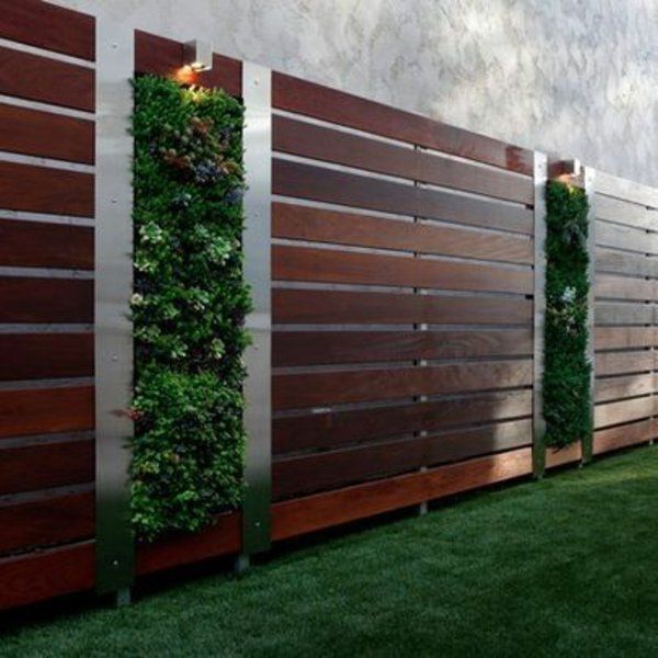 a fence with plants growing on it and some lights in the top right hand corner